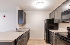 an empty kitchen with stainless steel appliances and black refrigerator