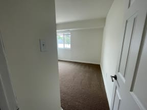 an empty room with a door open and a window in the background
