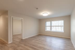 an empty living room with wood floors and a window