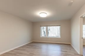 an empty living room with a window and wooden floors