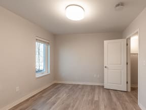 an empty living room with a white door and a window