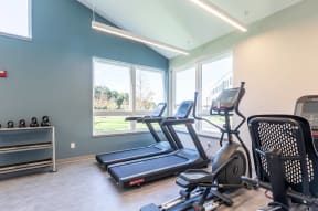 a gym with various exercise machines and windows