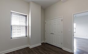 A room with a white door and a window with blinds.