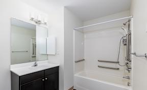 A white bathroom with a black vanity and a white bathtub.