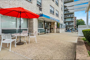 A red umbrella is on a patio table outside a building.