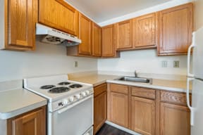 A kitchen with a white stove and wooden cabinets.