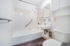 A white bathroom with a tub, sink, and toilet.