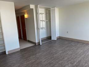 A room with a white wall and a grey floor with a white door.