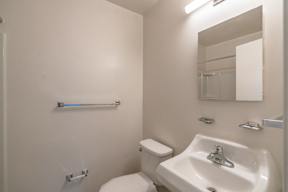 A white toilet sits next to a white sink in a small bathroom.