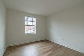 Empty room with a window and wooden flooring.