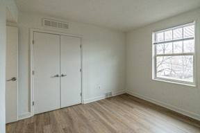 A room with a window and a wood floor.