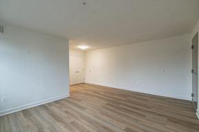 A room with wooden flooring and a door on the left side.