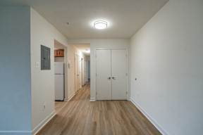 A long hallway with a refrigerator on the left and a door on the right.