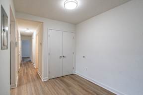 A hallway with white walls and wood floors.