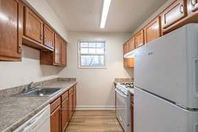 A kitchen with a white fridge and wooden cabinets.