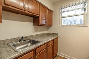 A kitchen with brown cabinets and a silver sink.