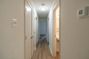 A long hallway with a light on the ceiling and a door on the right.