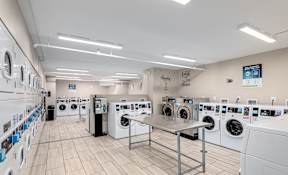 A laundromat with rows of washing machines and a sign that says "With Clean".