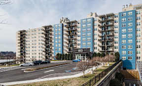 A view of a street with cars and apartment buildings.
