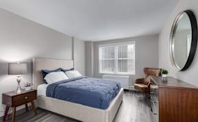 A bedroom with a bed, chair, and lamp.