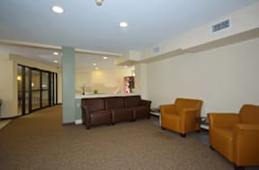 A waiting room with brown chairs and a white table.