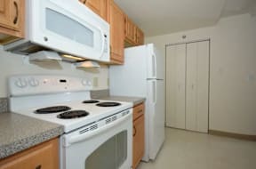 A kitchen with white appliances and wooden cabinets.