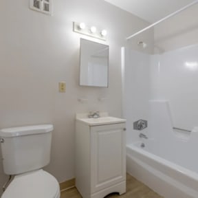 A white toilet sits next to a white sink in a small bathroom.