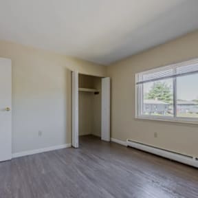 A room with a doorway leading to another room and a window with blinds.