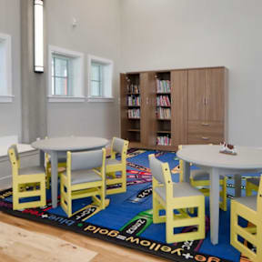 A room with a white table surrounded by yellow chairs.
