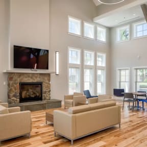 A living room with a stone fireplace and a television mounted above it.