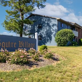 A sign that says "quire Village" in front of a building.