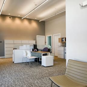 A room with a desk, chairs and a couch.