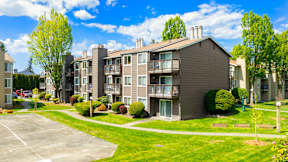 Apartment complex with a parking lot in front.