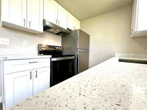 A kitchen with white cabinets and a granite countertop.
