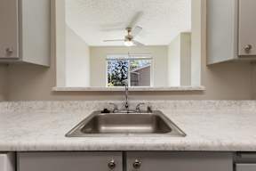 A kitchen with a marble countertop and a stainless steel sink.