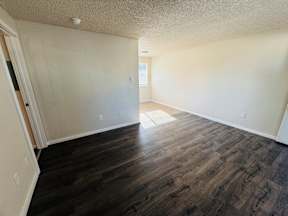A room with wooden flooring and white walls.