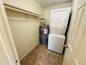 A small white toilet is in a small bathroom with a grey container next to it.