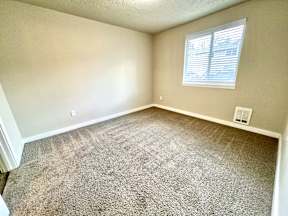 A room with a carpeted floor and a window with blinds.