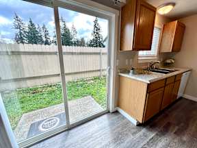 A kitchen with a wooden cabinet and a window overlooking a fence.