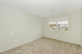 a bedroom with beige carpet and a large window  at Platt Gardens, West Babylon