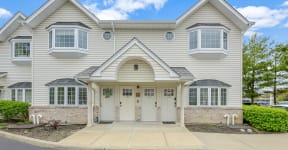 a large white house with two dormer windows and a white front door at Platt Gardens, West Babylon