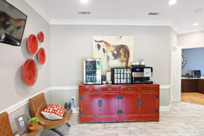 a red credenza with a coffee machine on top of it and a painting on the wall