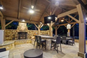 a covered patio with a fireplace and tables and chairs