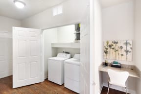 a room with a washer and dryer and a desk with a chair