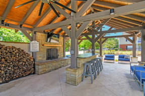 a covered patio with a fireplace and a bar with stools