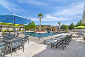 a swimming pool with chaise lounge chairs and umbrellas  at Reserve at Gulf Hills Apartment Homes, Ocean Springs, MS
