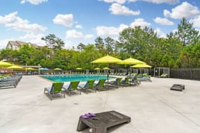 a swimming pool with green lounge chairs and yellow umbrellas
