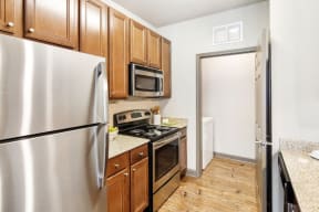 a kitchen with wooden cabinets and stainless steel appliances  at Kingston Crossing Apartment Homes, Louisiana