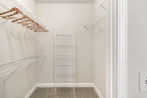 a small walk in closet with white walls and a white metal shelving unit