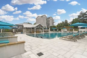 a pool with lounge chairs and umbrellas at the preserve at great pond apartments in winds  at Parkwest Apartment Homes, Hattiesburg, Mississippi